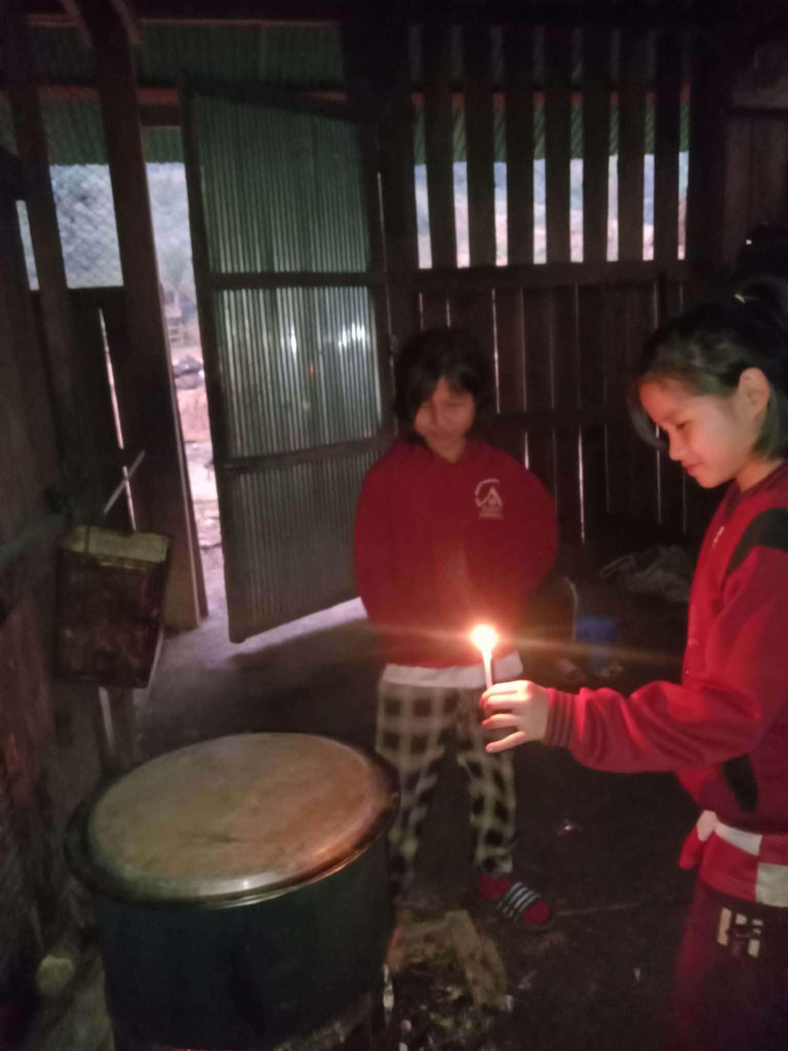 Children gather around candlelight to prepare dinner
