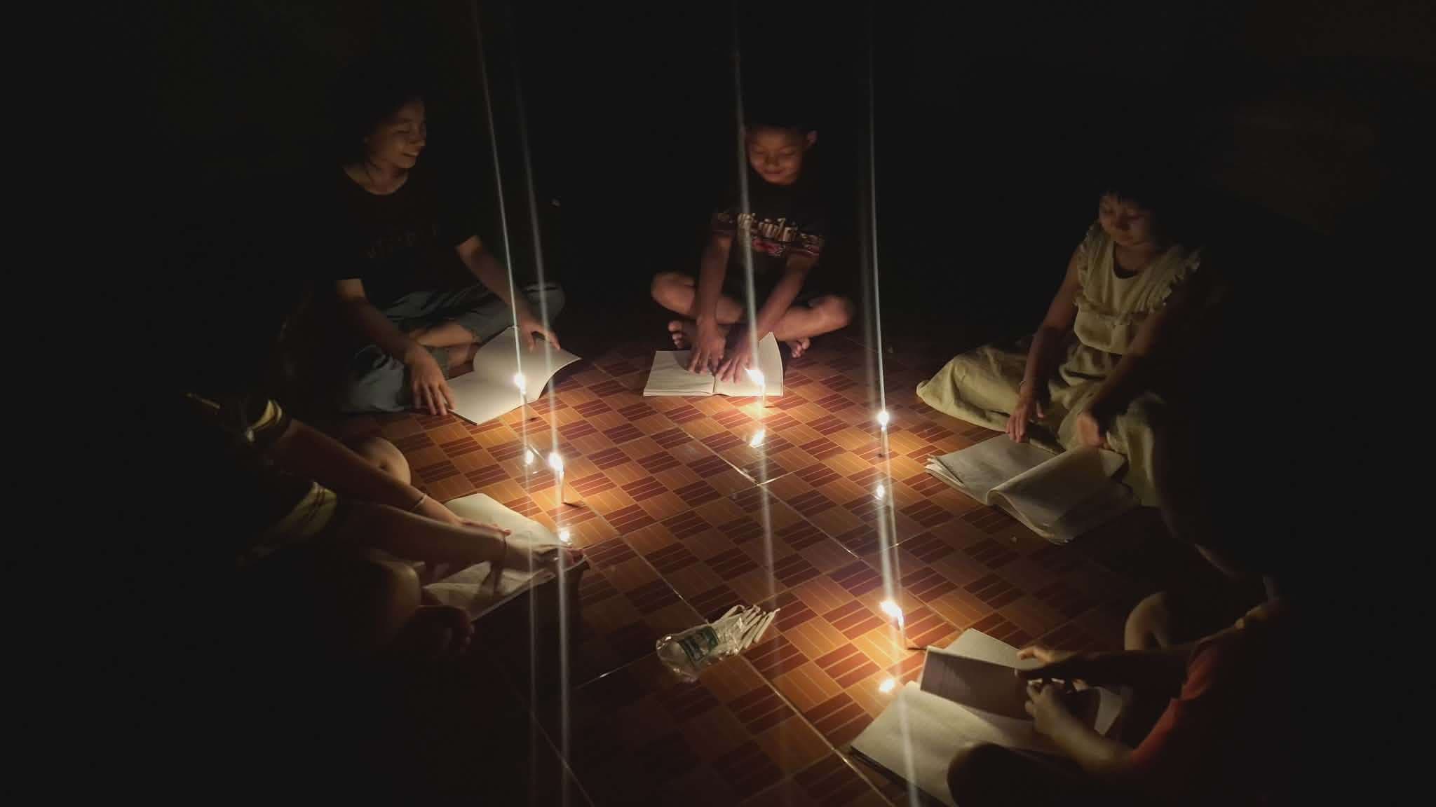 Children study under candlelight due to limited access to electricity