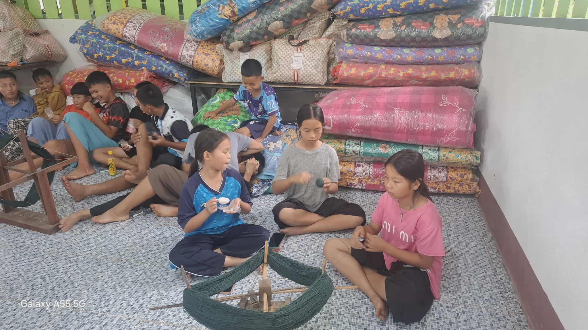Children in the project enthusiastically help to spin yarn and prepare equipment, embracing their roles in the crafting process!