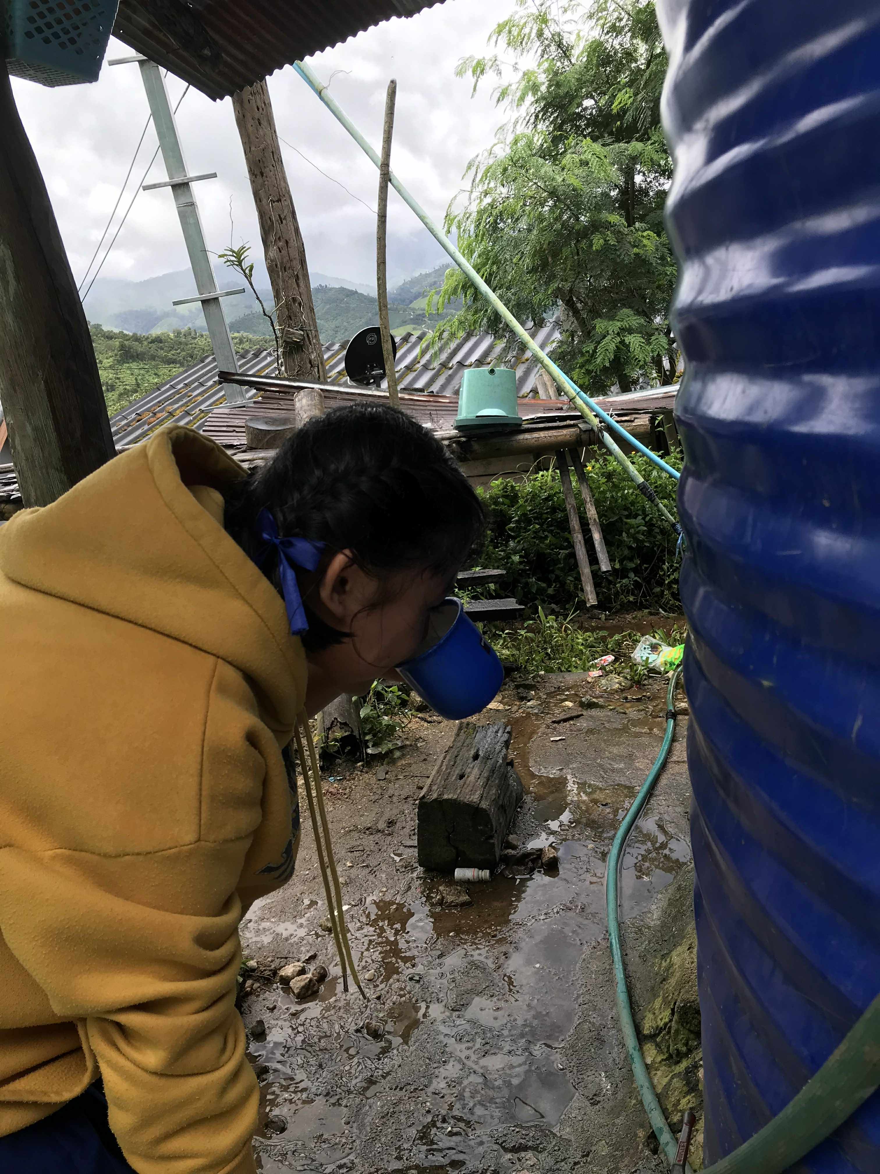 A child drinking directly from an unfiltered water tank, highlighting the need for clean and safe water access.