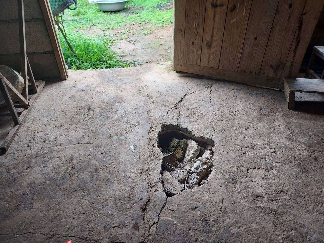 The image shows a hole in the cracked floor of the old building.