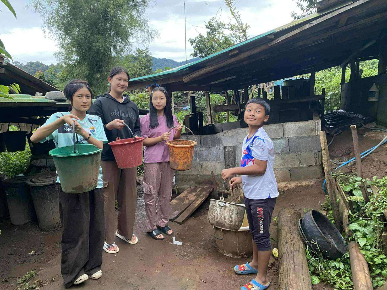 The children helped put the pig food in the bucket and gave it to the pigs.